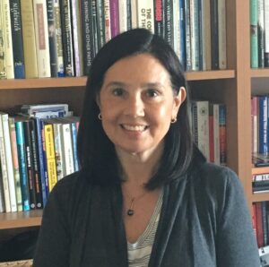 Portrait of Dr. Elena Sabogal standing in front of a bookshelf.