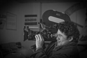 Élmer Salmerón operating a professional film camera in black and white.