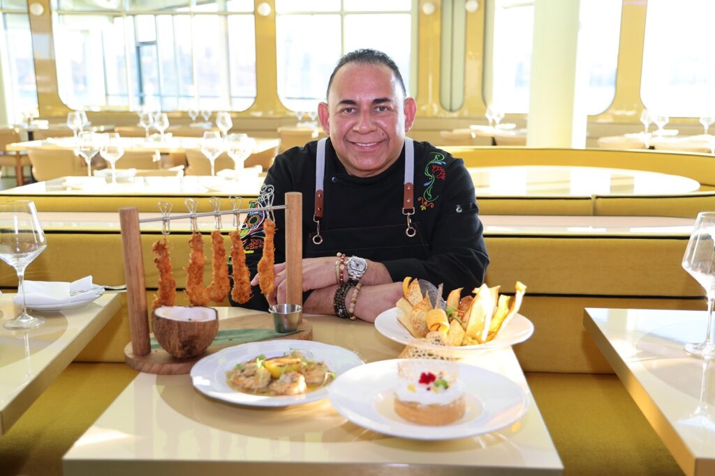 Chef Ricardo Cardona at Don Coqui restaurant table with several plated dishes in front of him.